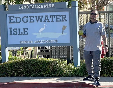 Edgewater Isle Senior Apartments employee smokes by sign